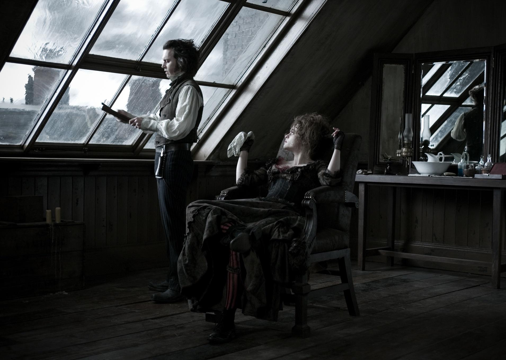 Johnny Depp sharpens his barber knife and Helena Bonham Carter sits in the chair talking with him.