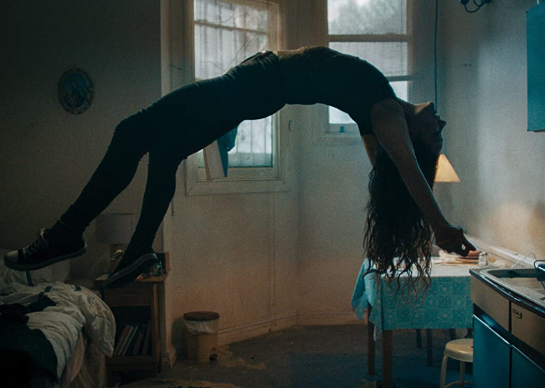 A levitating girl arched over backwards in a bedroom.