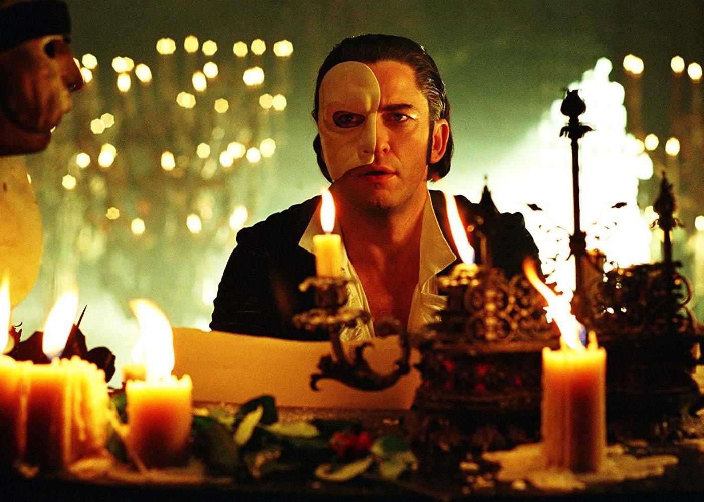 A man at a candlelit table wearing half a face mask.