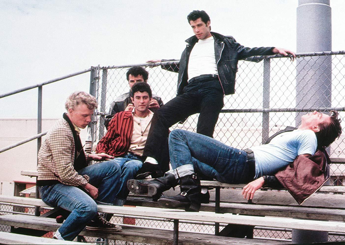 John Travolta and a group of guy friends hanging out on the bleachers.