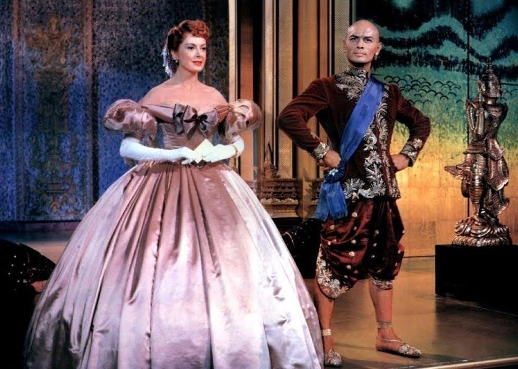 A woman in a ball gown smiling next to a king.