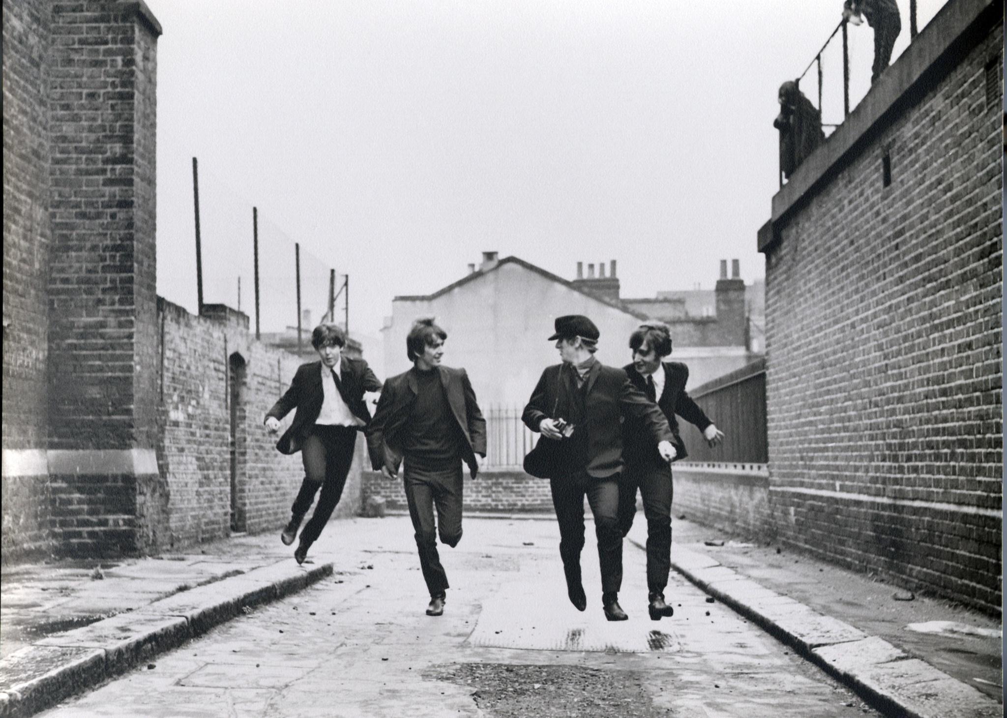 Paul McCartney, John Lennon, George Harrison, Ringo Starr running down a street.