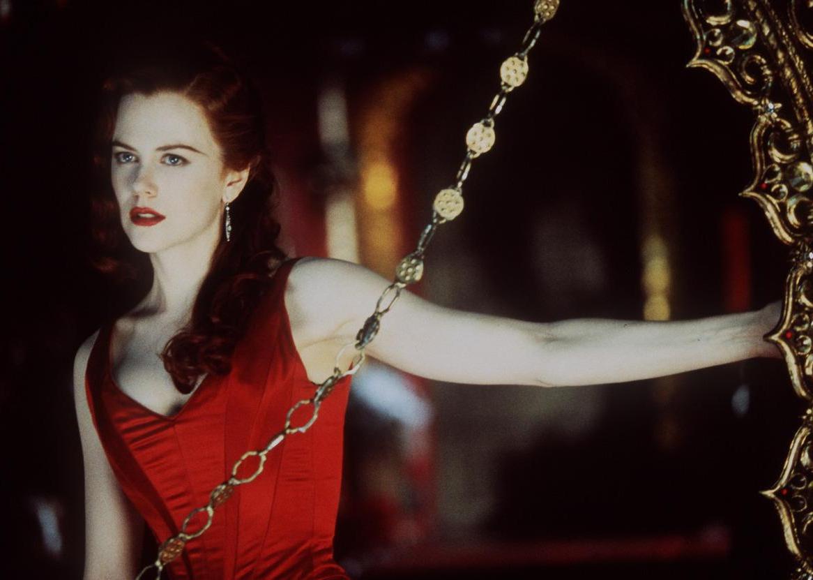 Nicole Kidman in a red dress next to a gold frame.