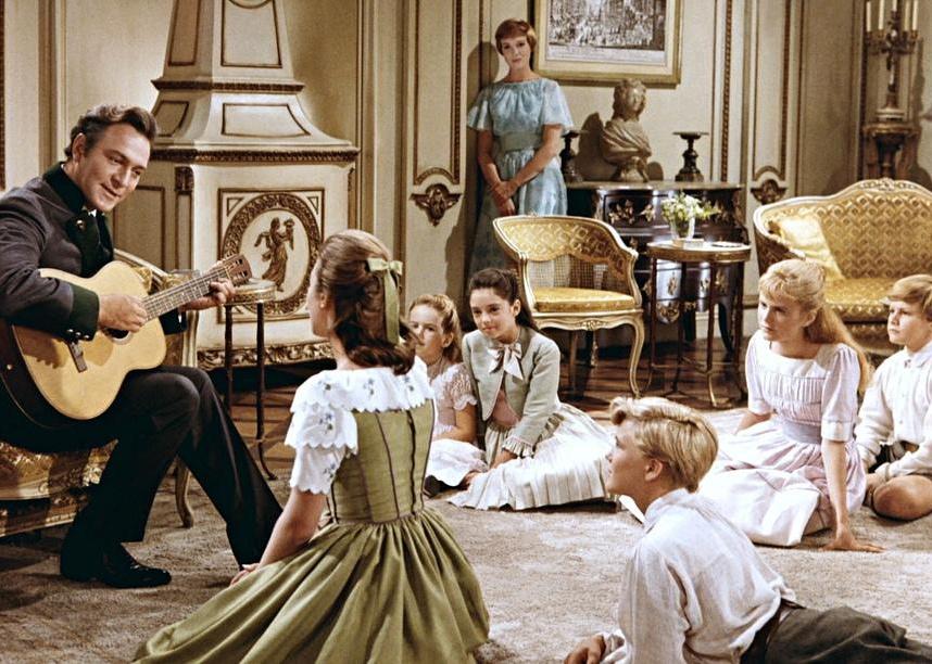 A man playing guitar to a room of children.