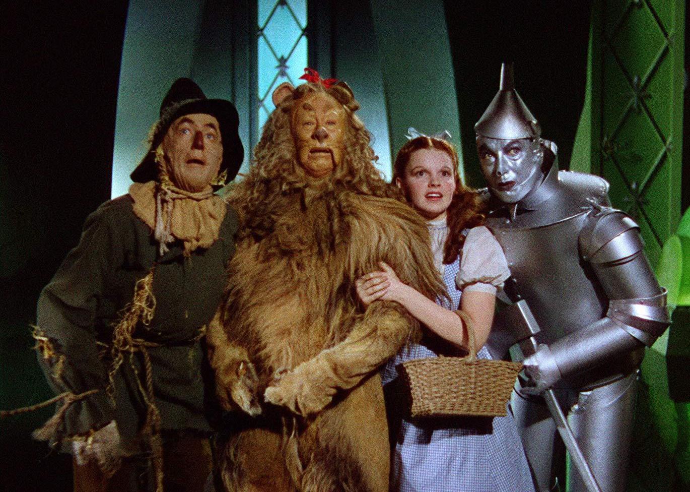 The scarecrow, lion, tinman and Judy Garland as Dorothy looking scared.