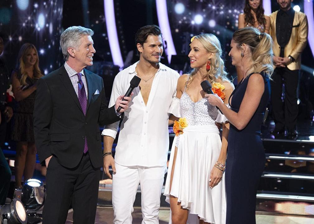 A man and woman in white are interviewed by the hosts of the show.