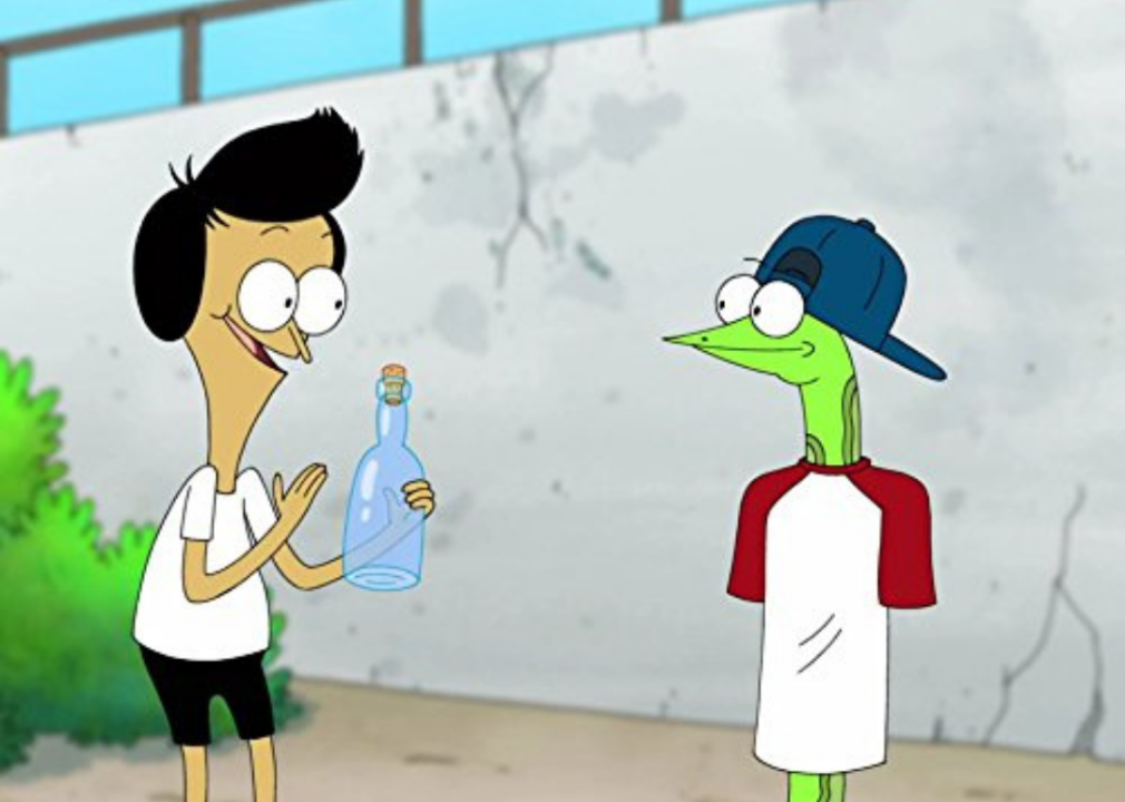 A boy holding an empty bottle and a snake wearing a t-shirt and cap.