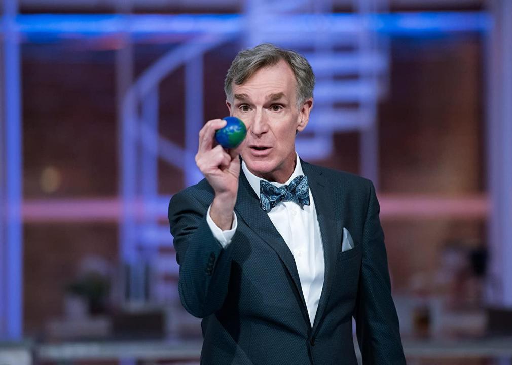 Bill Nye holds a tiny model of earth.
