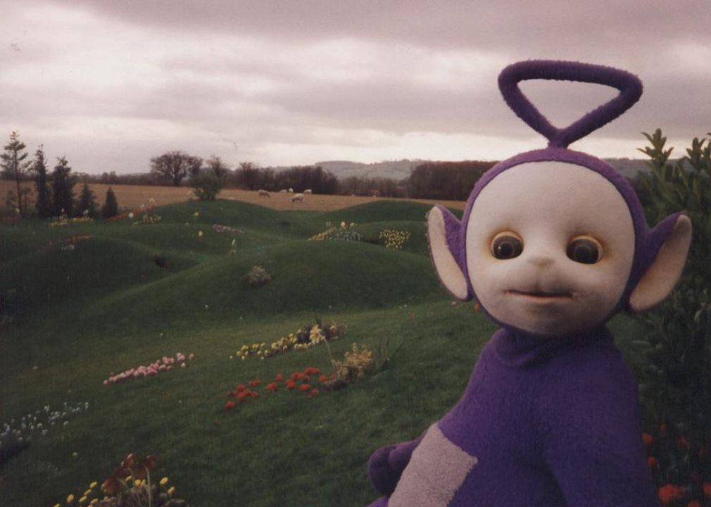 Teletubby in front of a field of flowers.