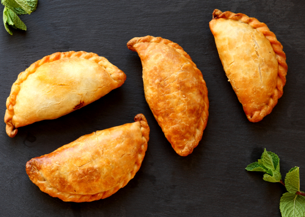 Four empanadas on a black background.