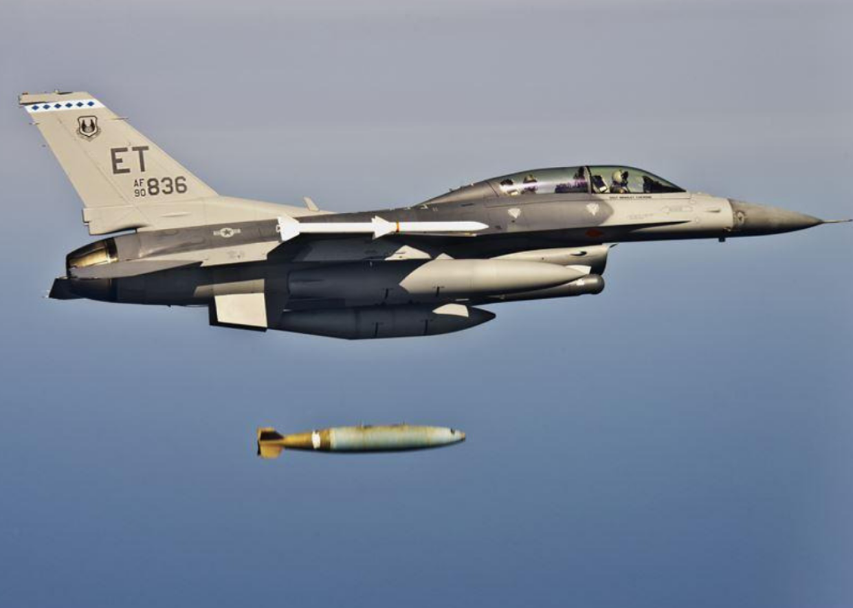 A military jet with a missile flying underneath.