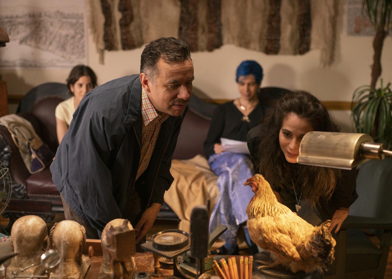 Fred Armisen and a woman looking closely at a chicken.