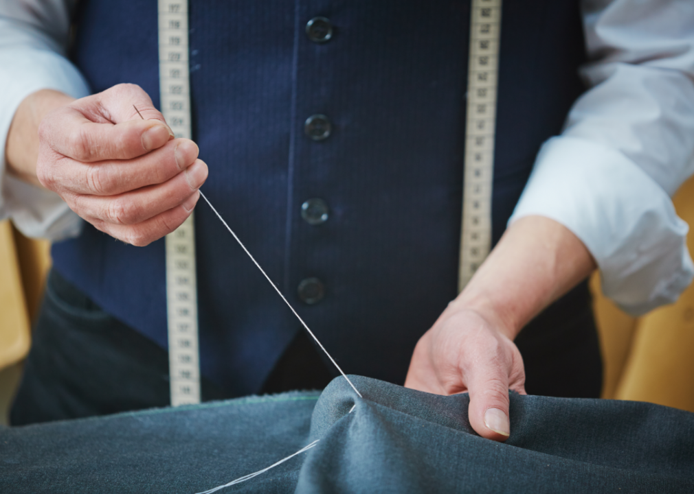 A worker hand sews some fabric.