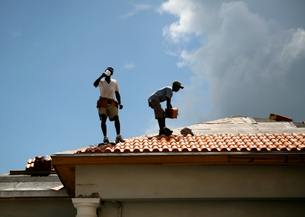 Roofers installing tiles on a roof
