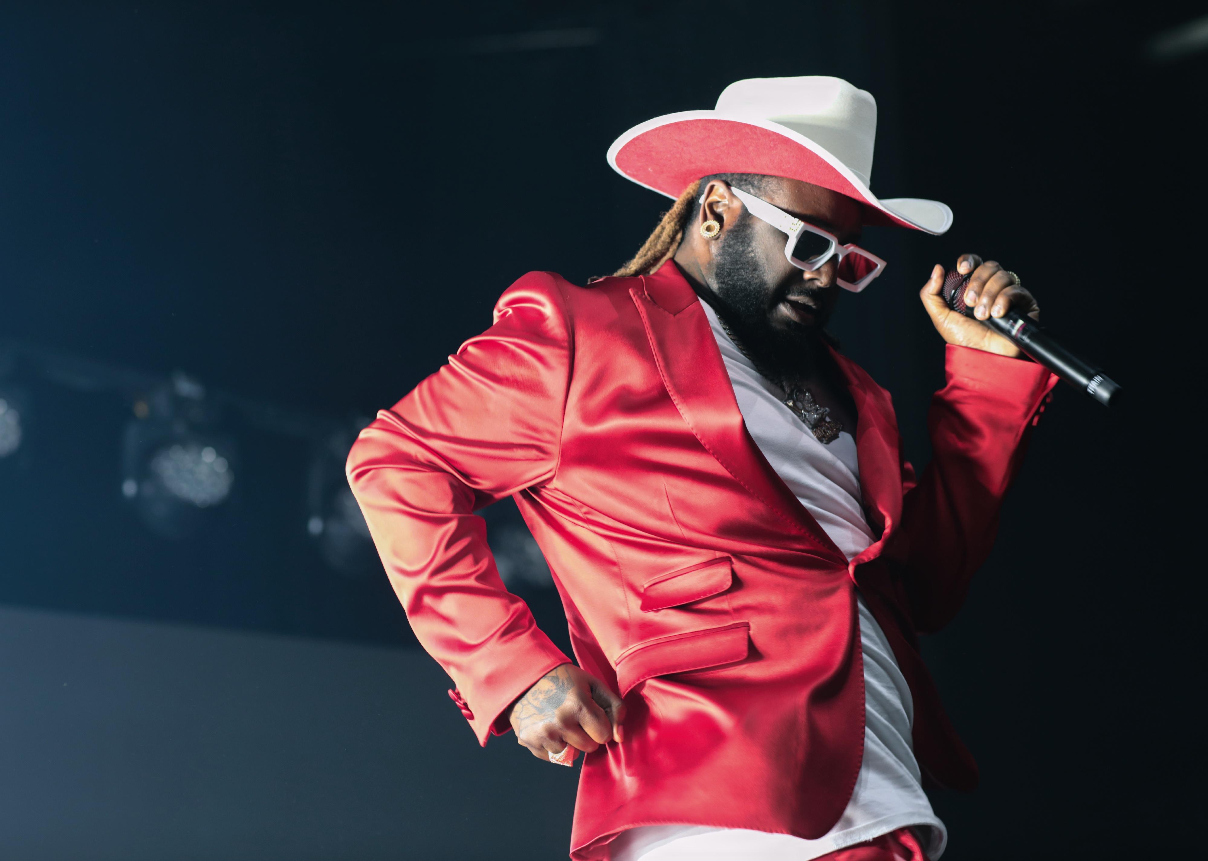 T-Pain in a red suit and red and white cowboy hat onstage.