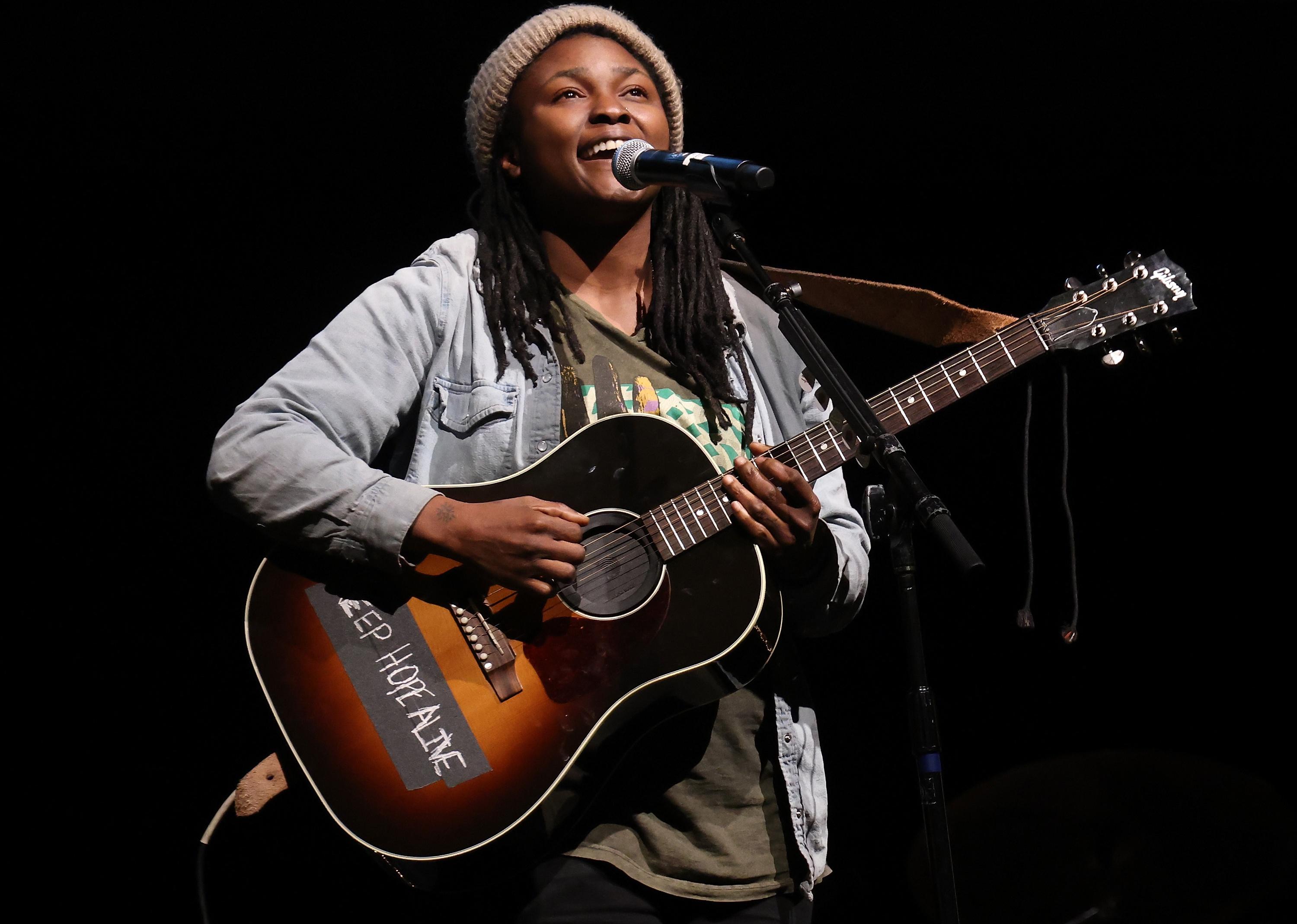 Joy Oladokun playing guitar onstage.