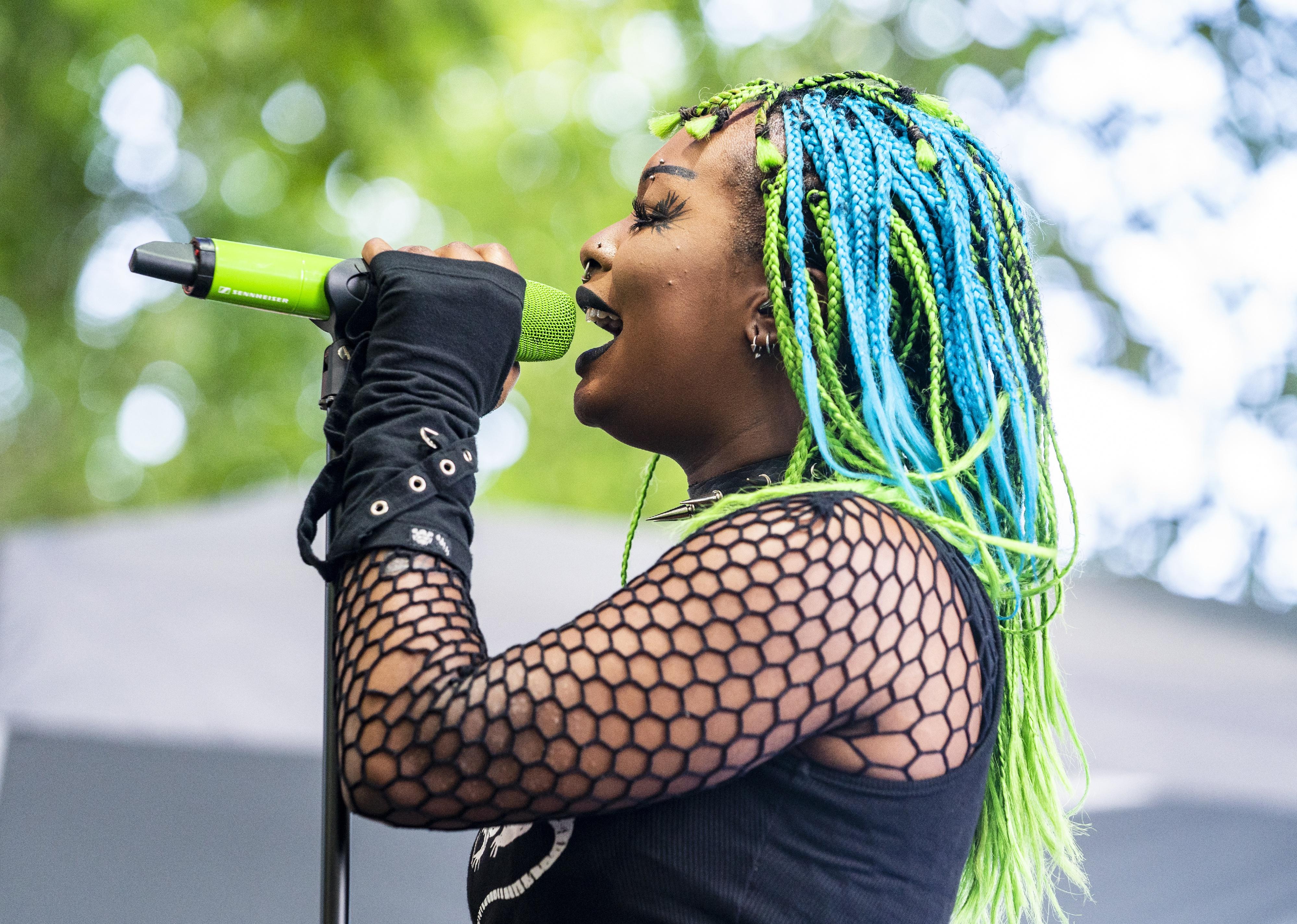 Edith Victoria of Meet Me @ The Altar performing in a fishnet top and blue and green braids.