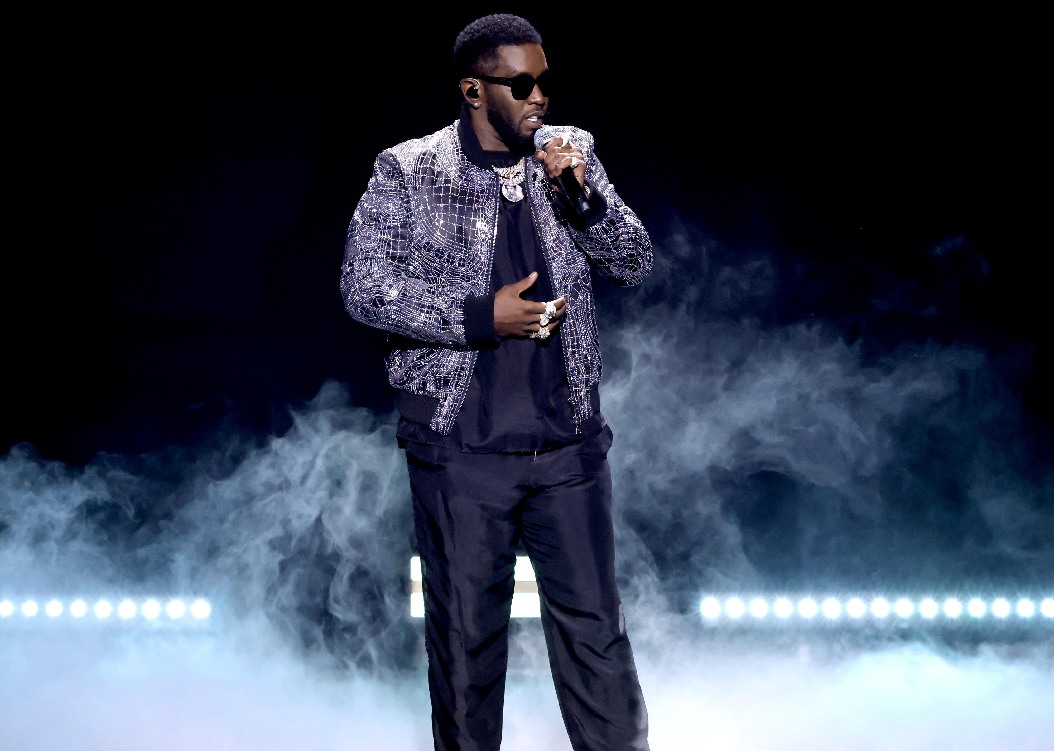 Diddy in smoke onstage in silver and black.
