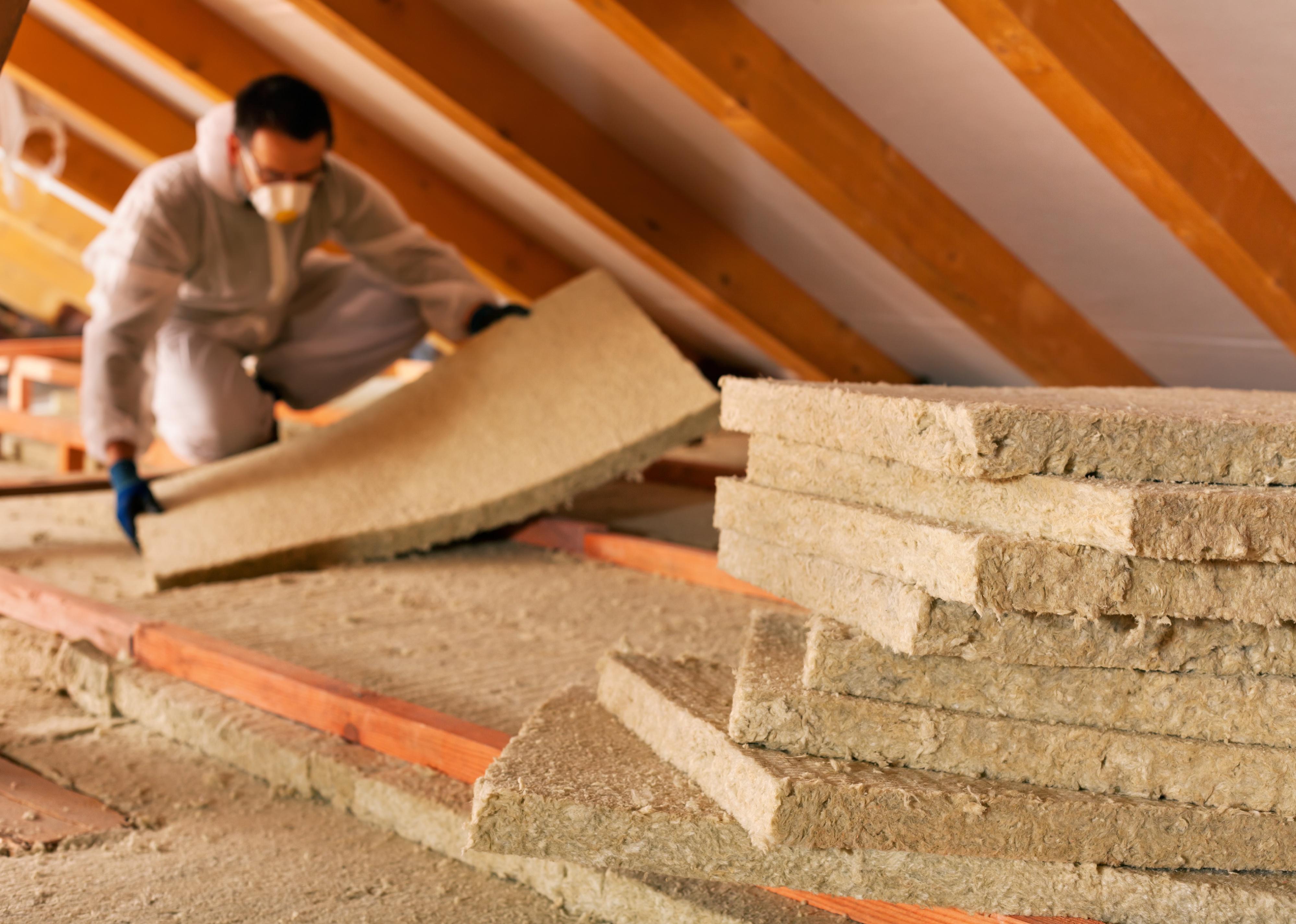 Worker installing insulation in an attic