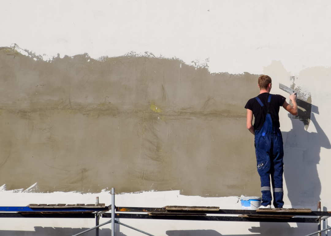 Plasterer works on the side of a structure