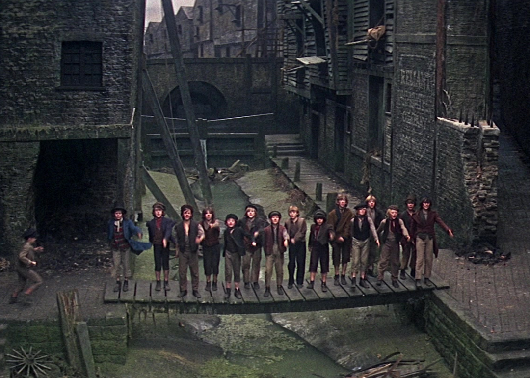 A line of young boys standing on a bridge surrounded by stone buildings.