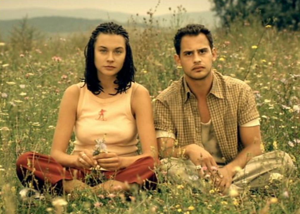 A man and woman sit in a field of wildflowers.