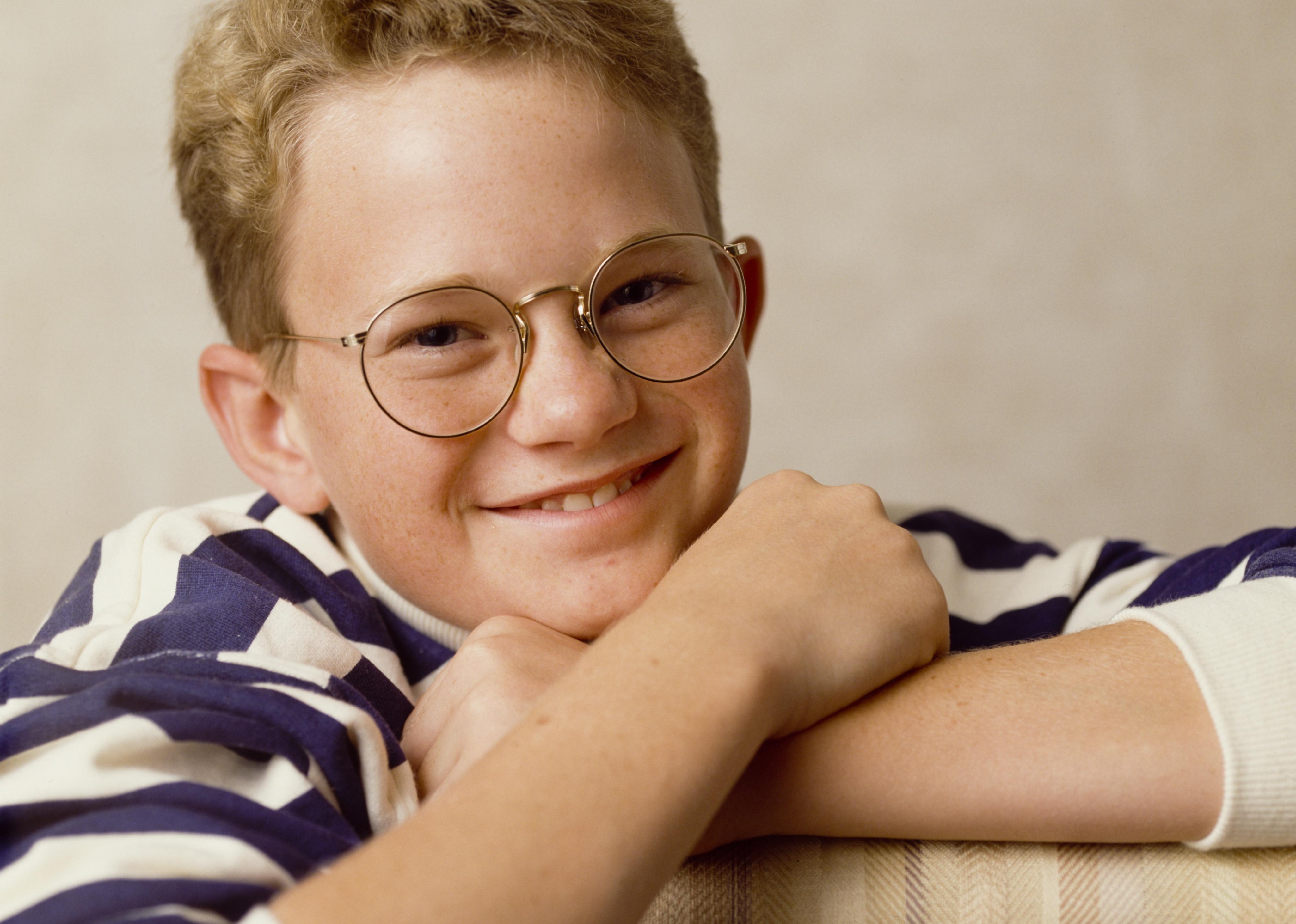 Neil Patrick Harris posing in a blue and white striped shirt and glasses.