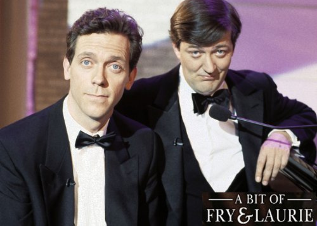 Stephen Fry and Hugh Laurie in suits onstage.