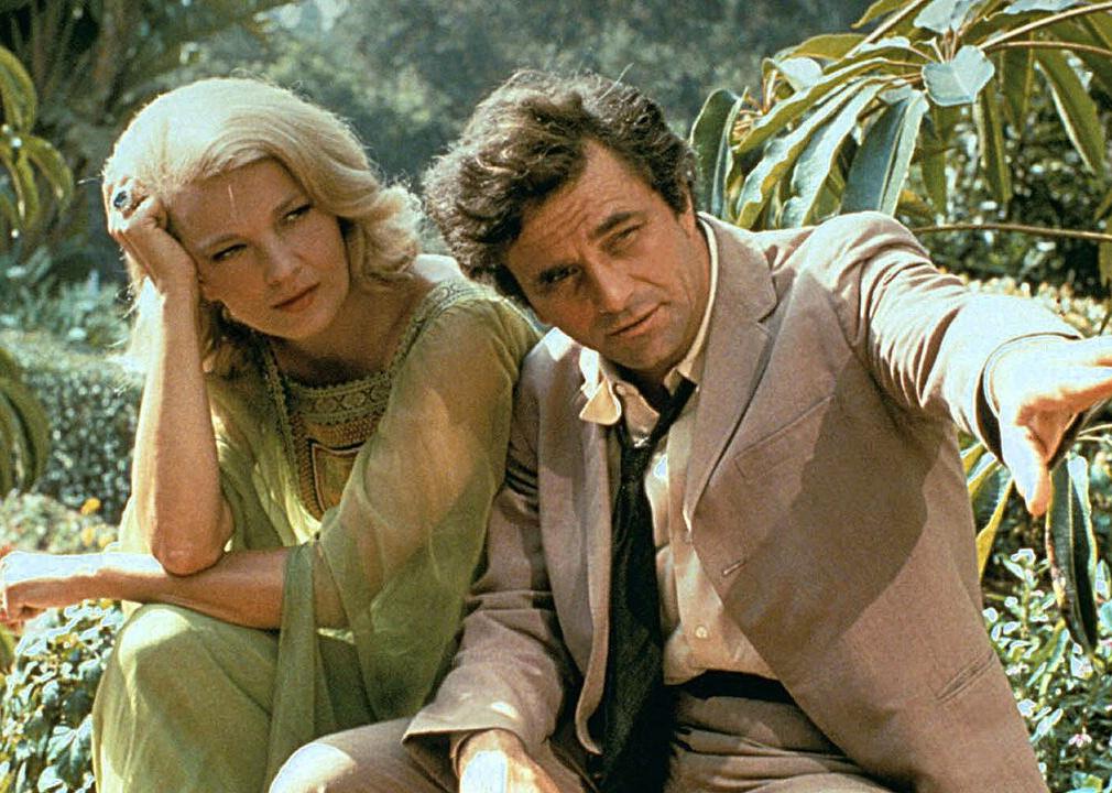 Peter Falk and Gena Rowlands sitting outside in front of tropical plants.