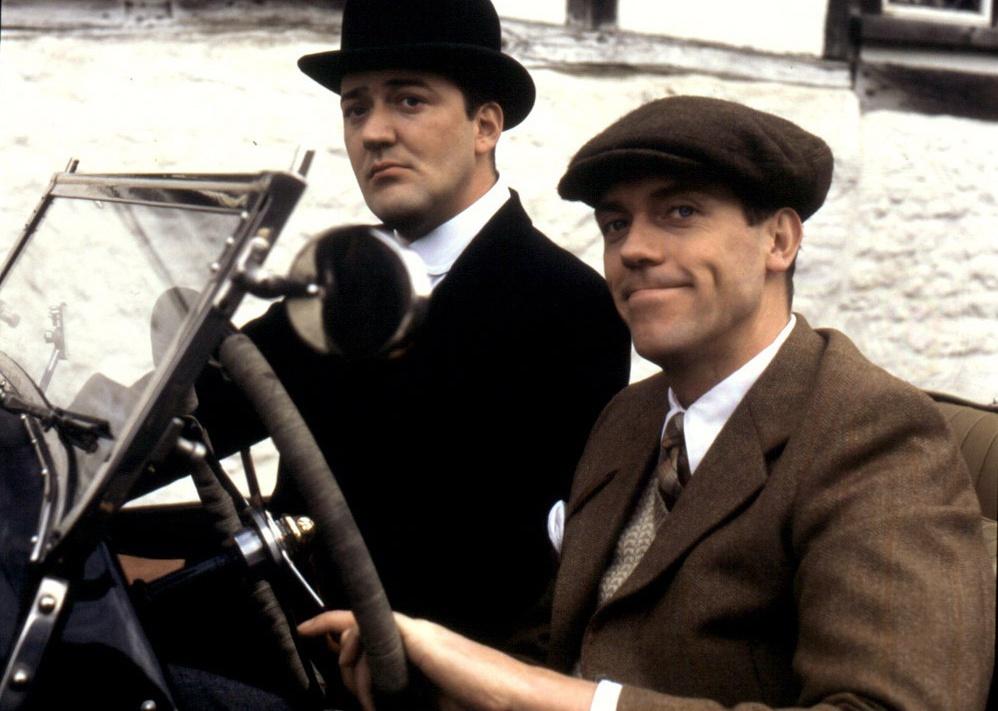 Stephen Fry and Hugh Laurie driving an antique car.