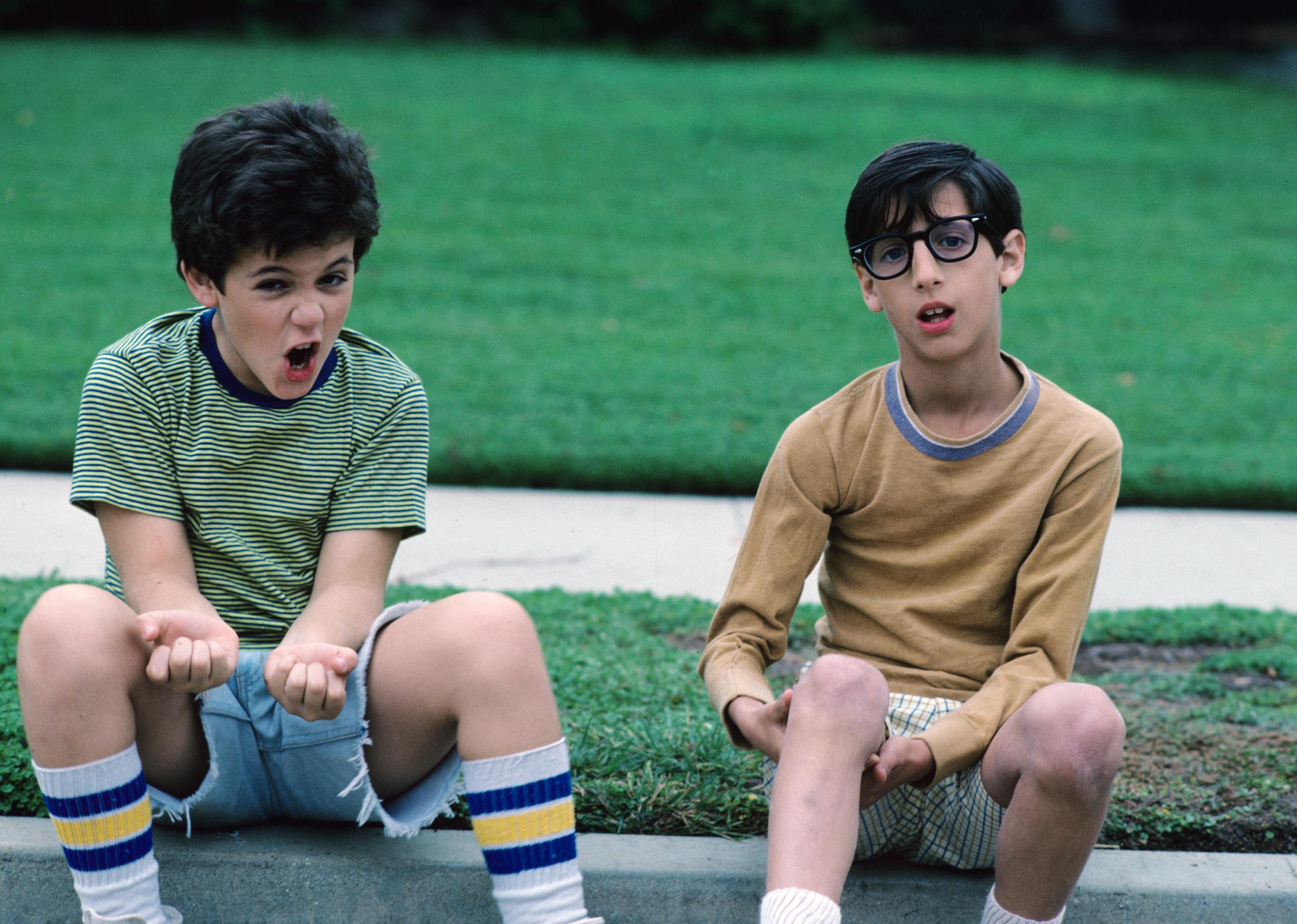 Fred Savage and Josh Saviano, as kids, sit on a curb.
