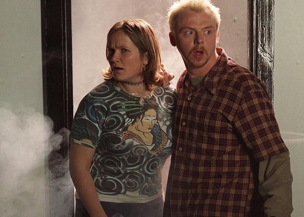 Simon Pegg and Jessica Hynes standing in a doorway with smoke rising from their feet.