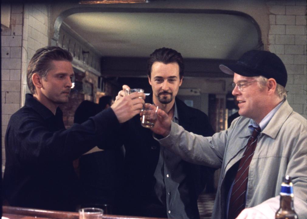 Philip Seymour Hoffman, Edward Norton, and Barry Pepper toast with a shot at a bar.