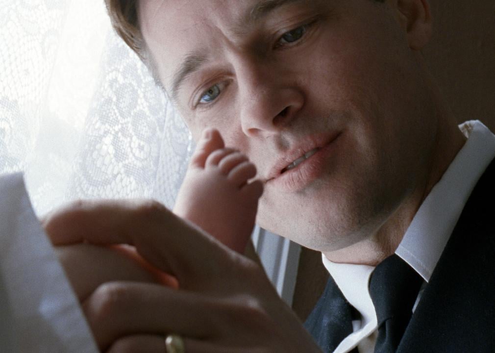Brad Pitt gazes down in awe while holding a baby's foot.