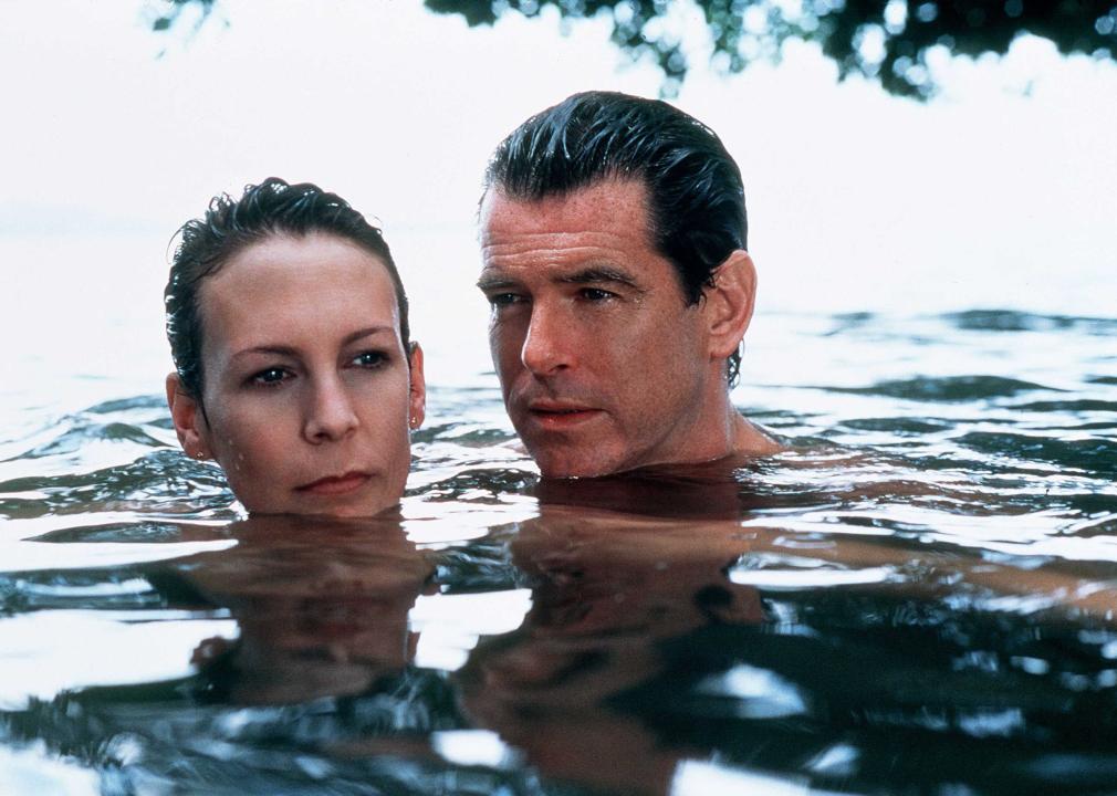 Pierce Brosnan and Jamie Lee Curtis swimming in the water with only their heads above water.