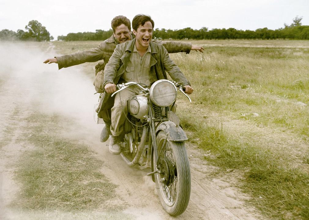 Rodrigo de la Serna and Gael García Bernal laughing and riding a motorcycle.