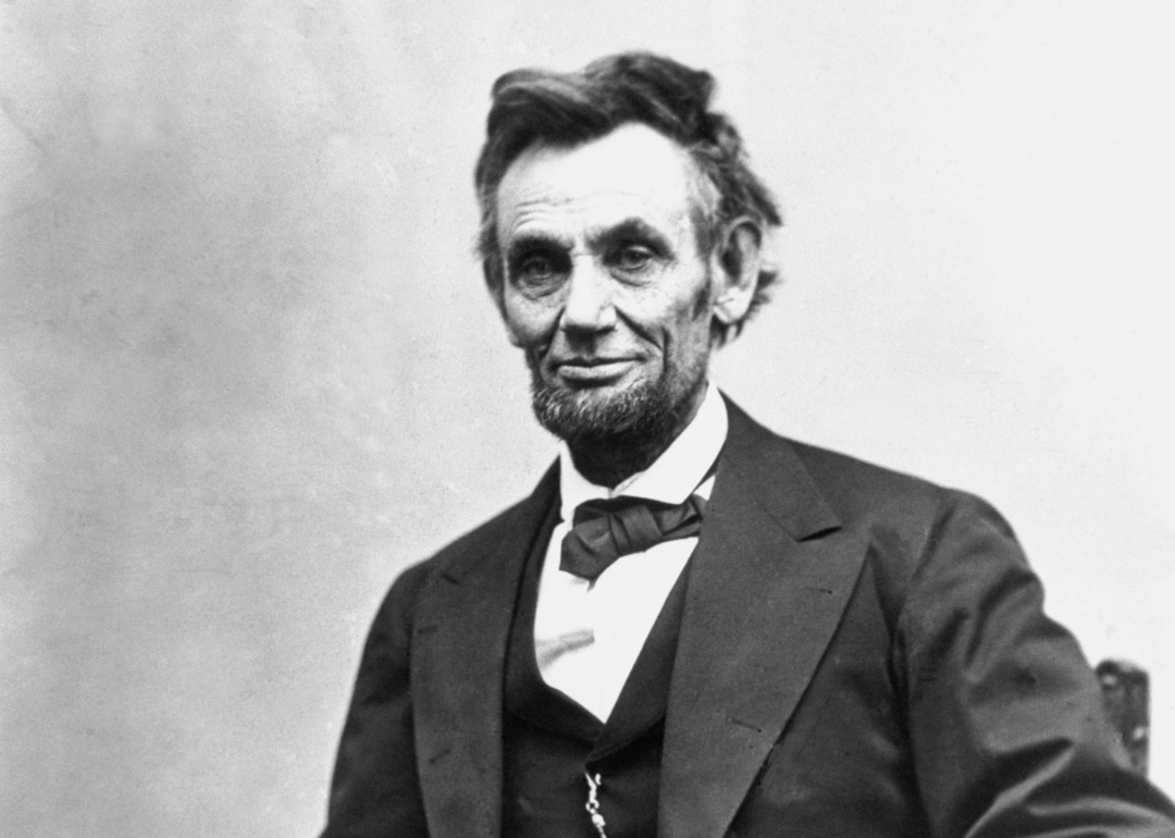 Abraham Lincoln in a suit sitting in a chair.