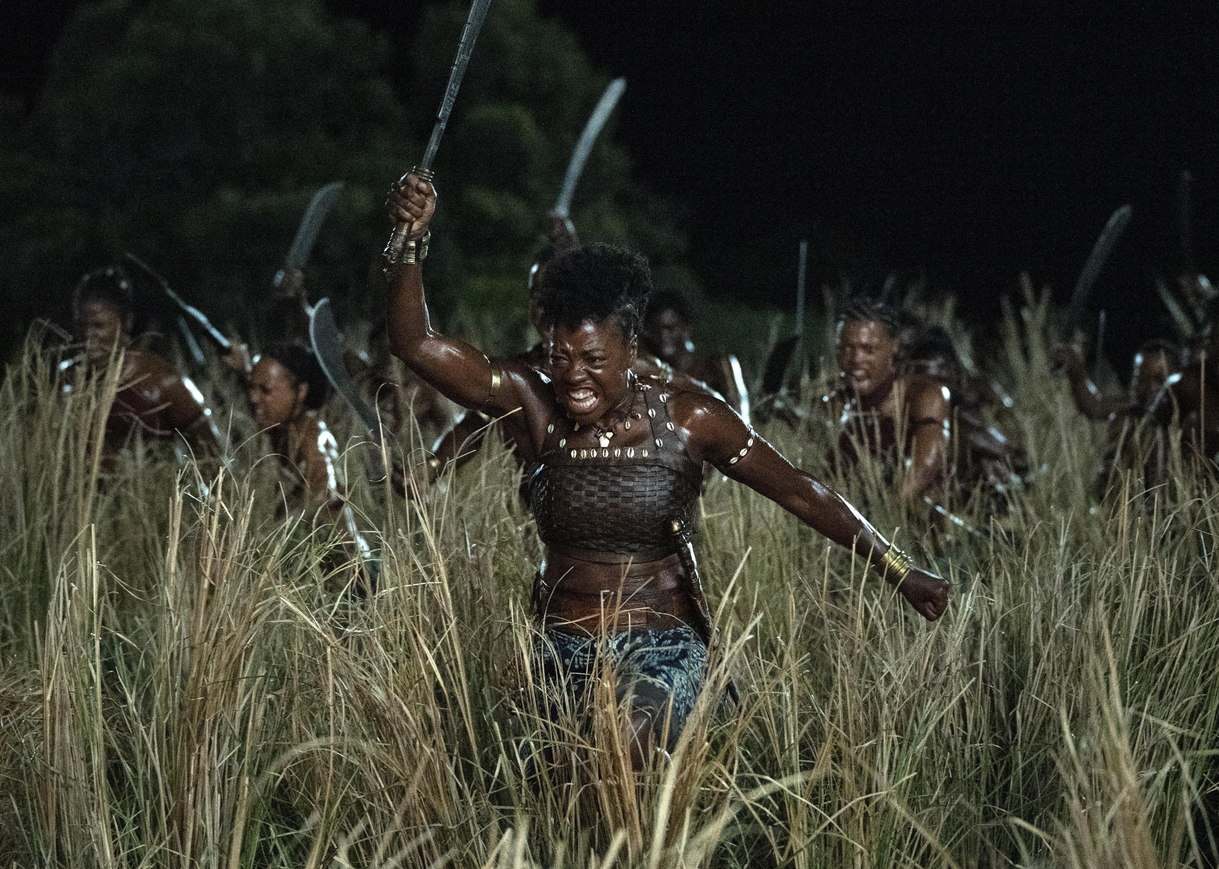 Viola Davis ready marching to battle with a machete in a field of women.
