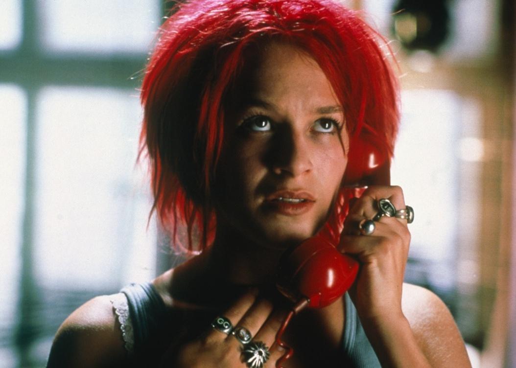 Franka Potente with bright red hair talking on a red phone.