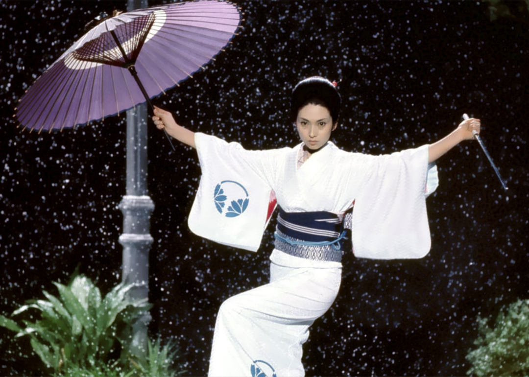 A woman in a kimono holding an umbrella and a weapon.