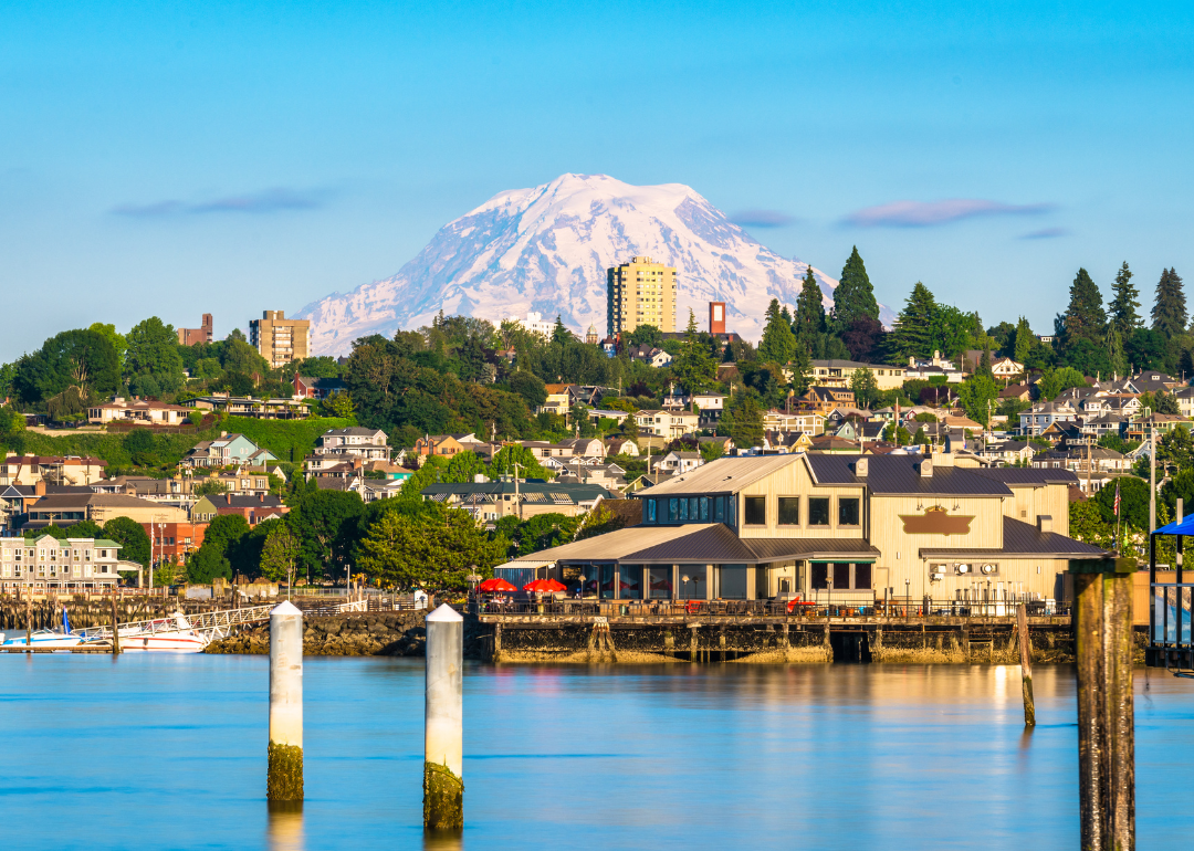 Homes and businesses on a hill in Tacoma with mountains in the background.