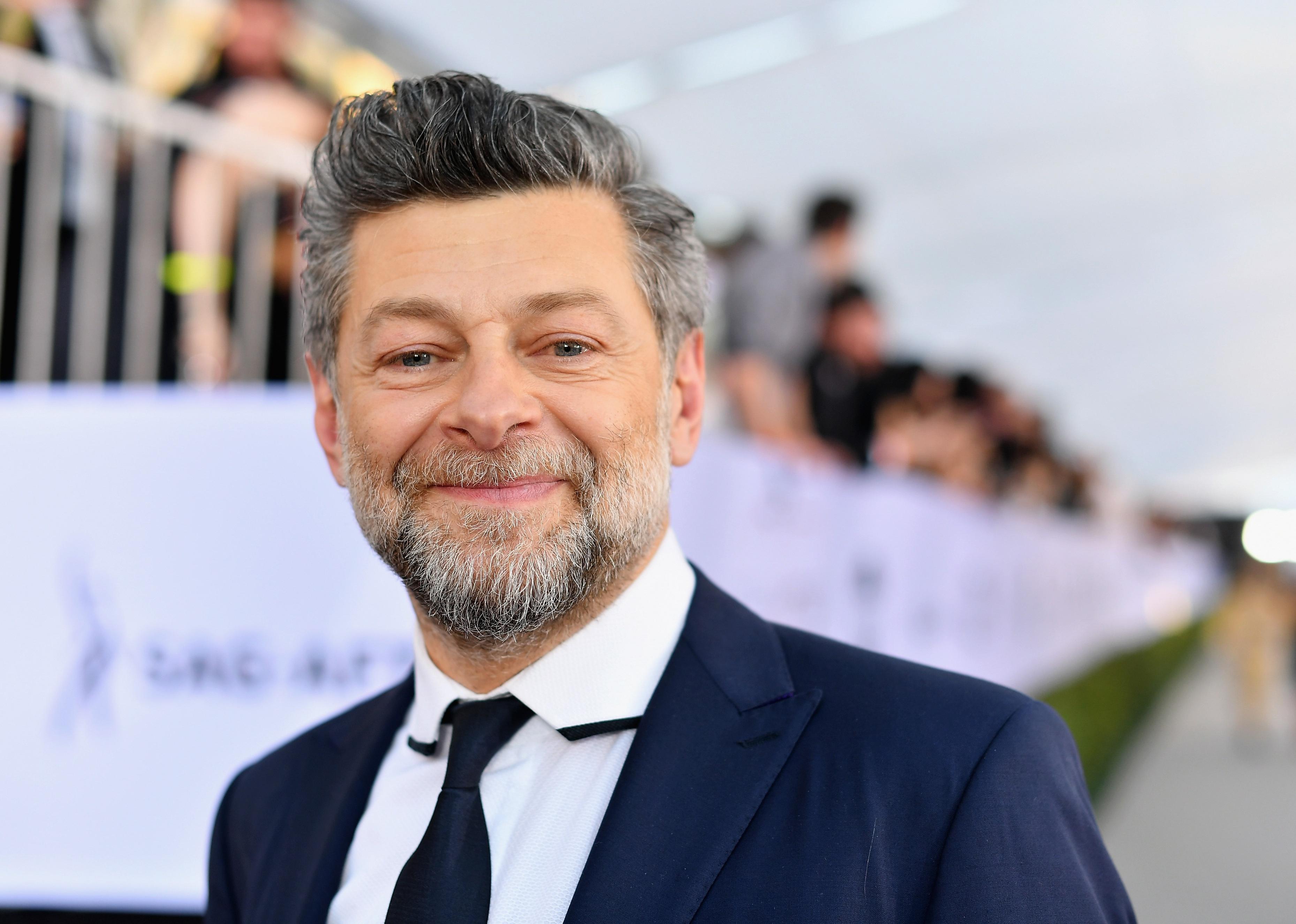 Andy Serkis in a navy suit.