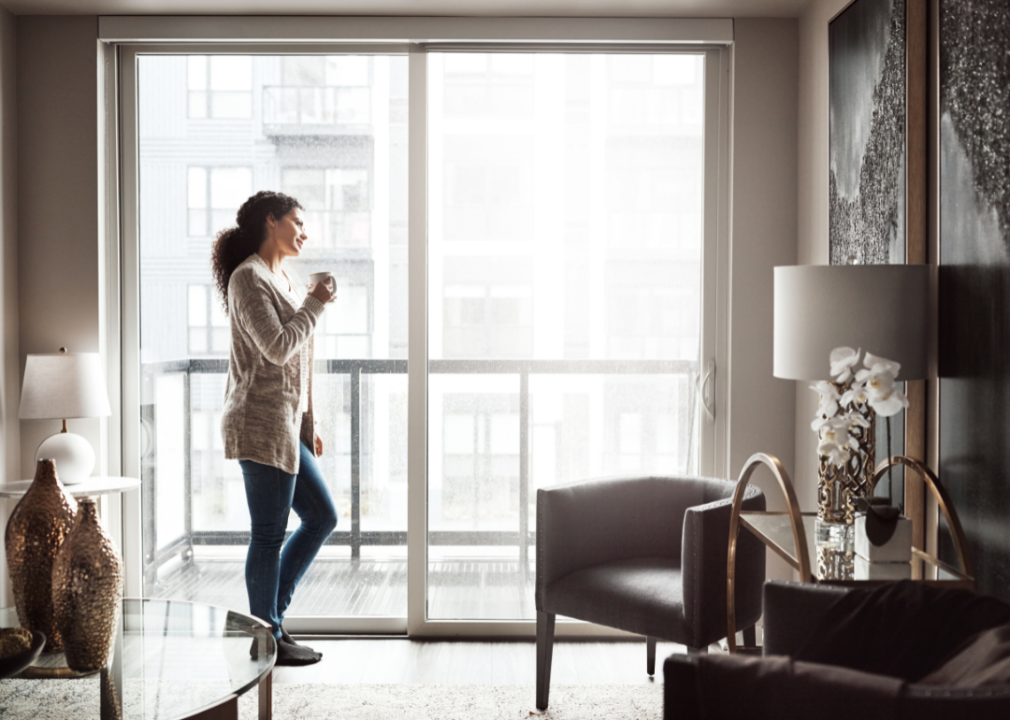 A woman looking out the window of her apartment.