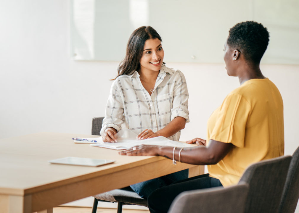 One woman interviewing another at a desk.