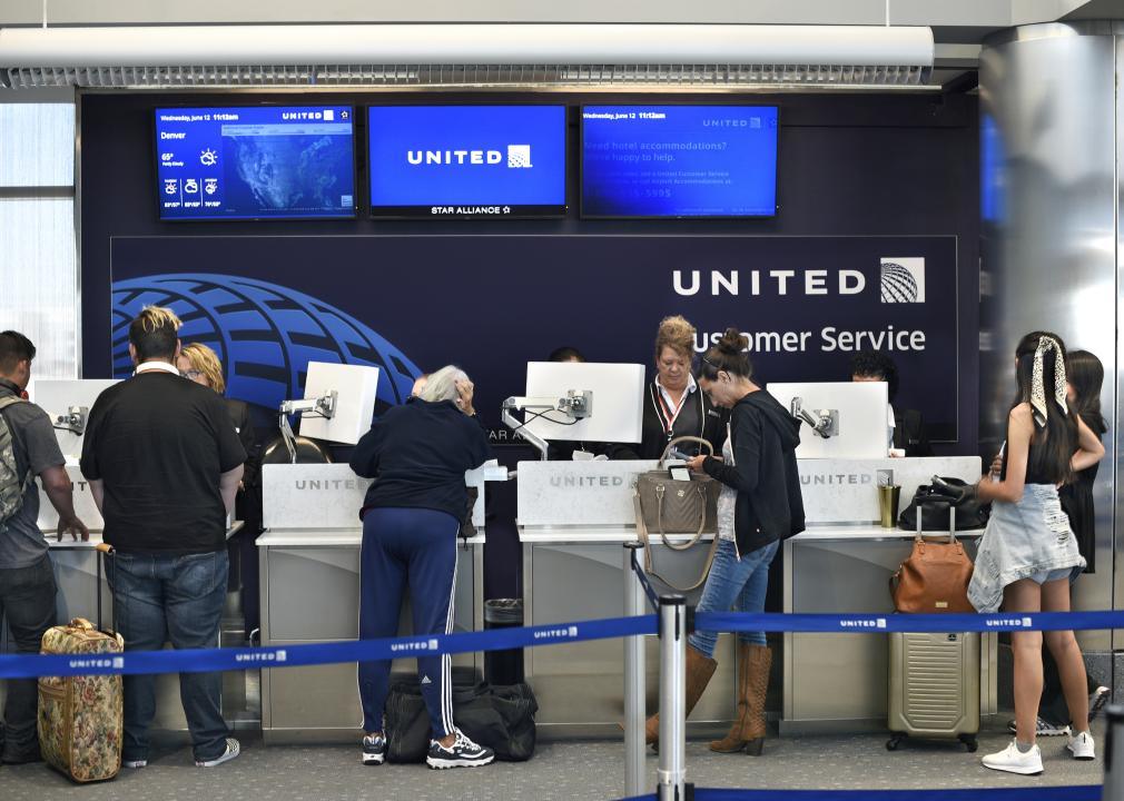 Travelers stand in line at the United Airlines customer service desk.