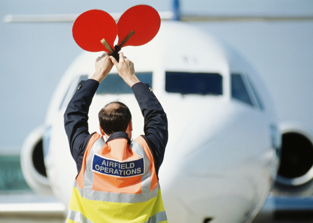 A man directs an aircraft on the runway.