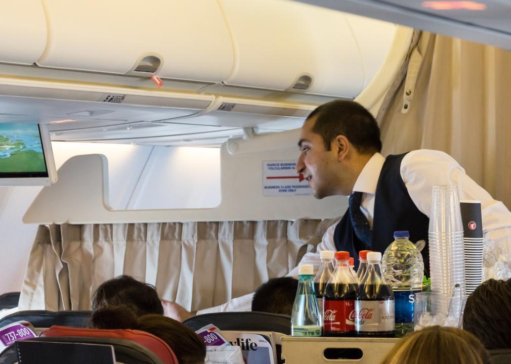 Flight attendant serves beverages to guests.