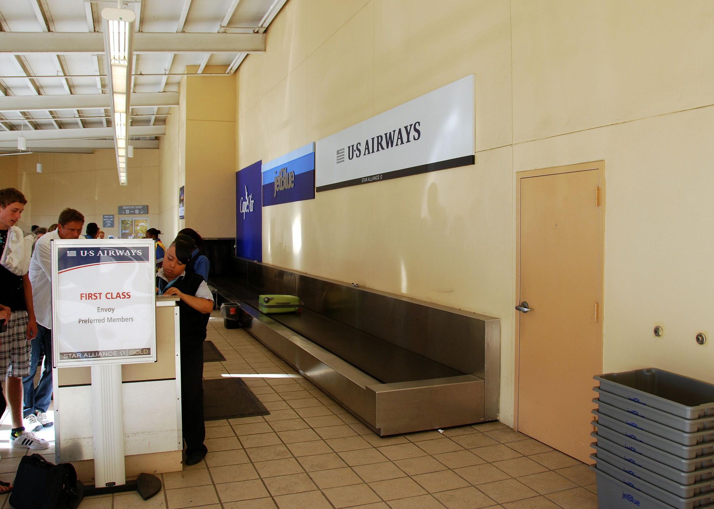People standing at a first class airport kiosk in a small airport.