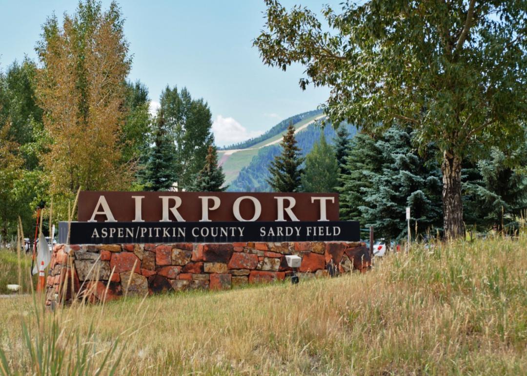 A stone entrance sign into Aspen airport with mountains in the background.