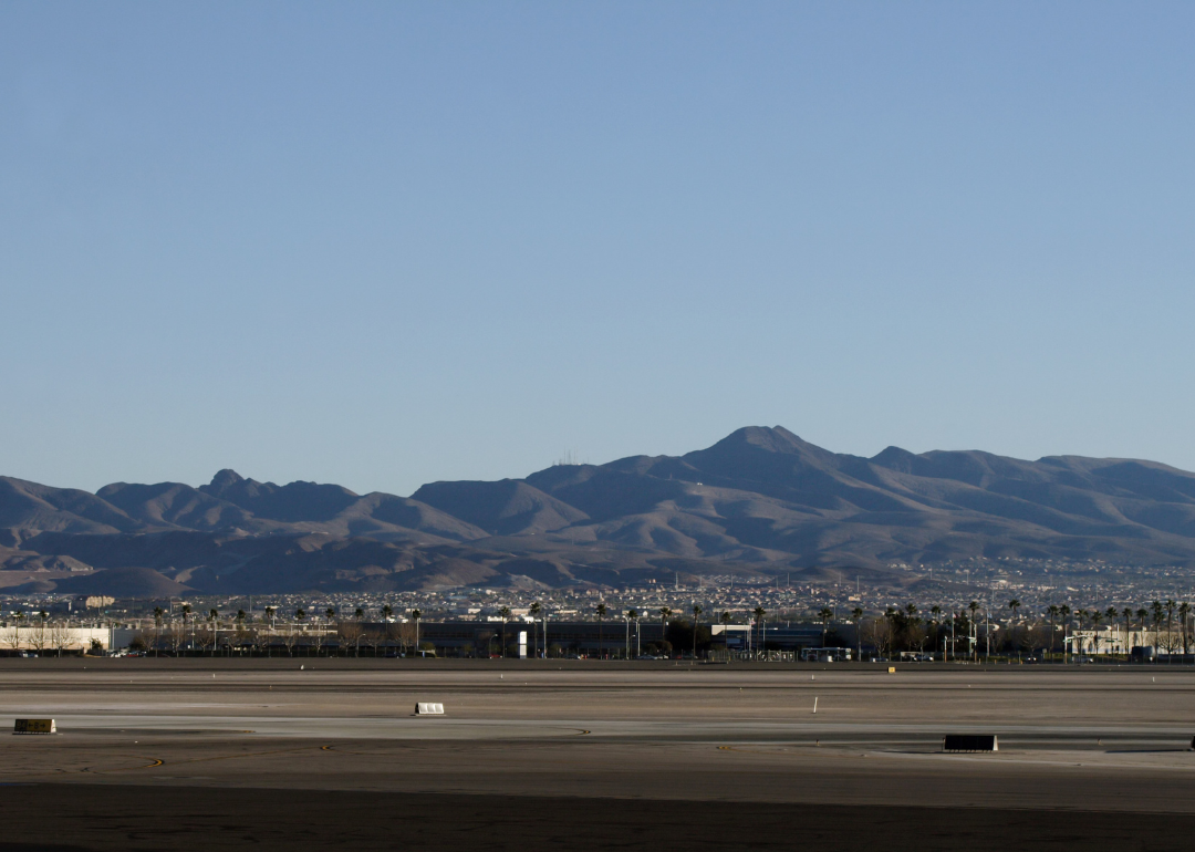 A runway at McCarran airport with mountains in the background.